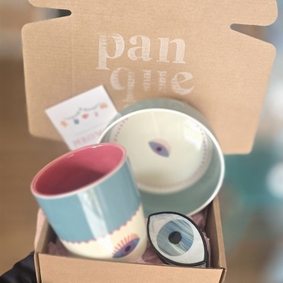 Conjunto de caneca, prato e objeto em forma de olho dentro de caixa de cartão