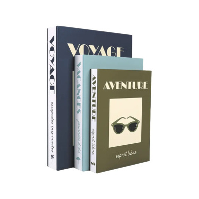 Três livros decorativos empilhados com capas azul escuro, azul claro e verde-oliva e texto em francês.