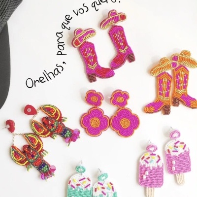 Seis pares de brincos coloridos artesanais sobre fundo branco com texto em círculo.