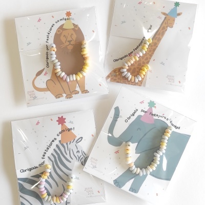 Pulseiras coloridas em embalagens com ilustrações de leão, girafa, zebra e elefante.