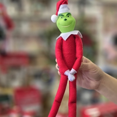 Boneco do Grinch com chapéu de Natal vermelho e roupagem vermelha em fundo desfocado