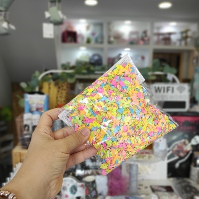 Saco plástico com confetes coloridos segurado por mão em loja