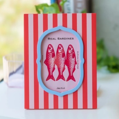 Moldura de fotografia vermelha com riscas brancas e borda azul, imagem de sardinhas vermelhas no centro.