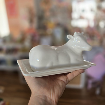 Vaso de cerâmica branco em forma de vaca numa base retangular