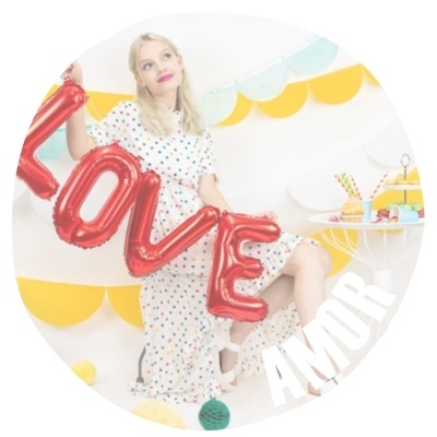 Mulher de vestido branco com balões vermelhos LOVE e decoração amarela com cupcakes