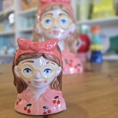 Cabeça de cerâmica cor-de-rosa com padrão de cerejas e óculos amarelos