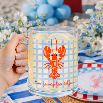 Caneca de vidro com lagosta e texto, contendo limonada, numa mesa decorada ao ar livre