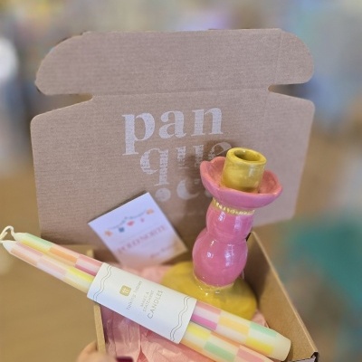 Caixa de cartão aberta com castiçal cerâmico e velas coloridas