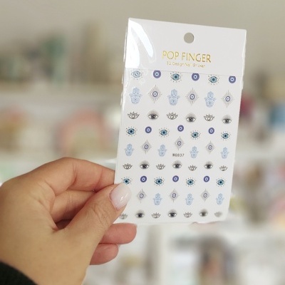 Cartela de stickers decorativos com vários desenhos de olhos e símbolos em cores azul, preto e branco.