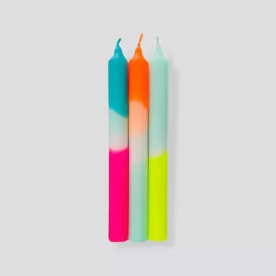 Três velas coloridas com design em três tons sobre fundo cinzento