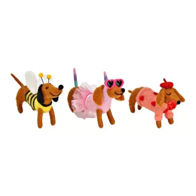 Três cães de peluche castanhos com fantasias coloridas divertidas