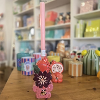 Suporte cerâmico decorativo com vela rosa numa loja