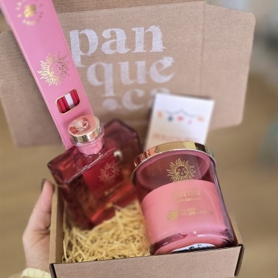 Conjunto de produtos rosa com detalhes dourados embalados numa caixa de cartão castanho.