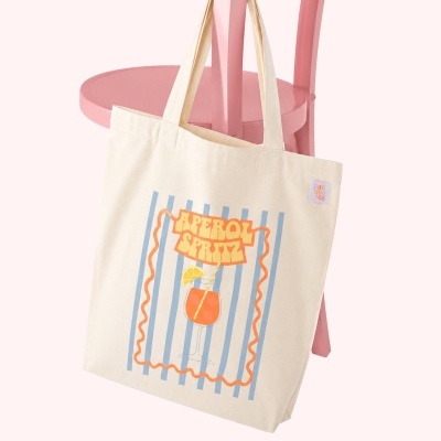 Saco de pano bege com design Aperol Spritz pendurado em cadeira rosa