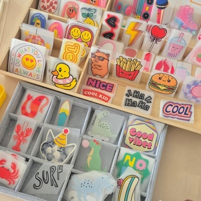 Autocolantes coloridos de silicone com vários desenhos e textos em organizador de madeira e tecido cinza