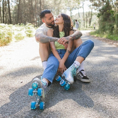 Casal sentado na estrada, mulher com patins de rodas azuis e homem com ténis