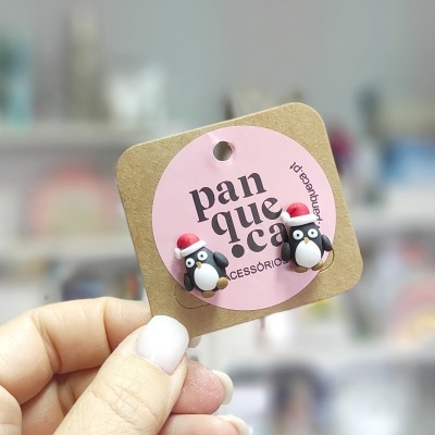 Brincos de pinguim de Natal pendurados em cartao