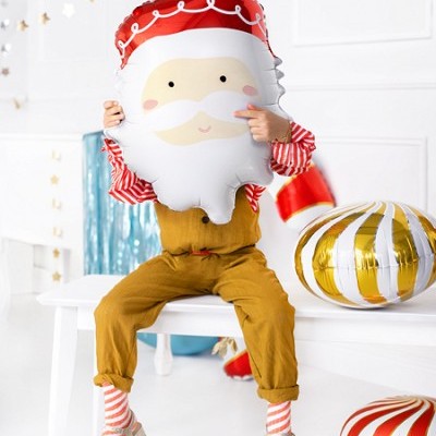 Balão decorativo do Pai Natal segurado por criança sentada num banco branco