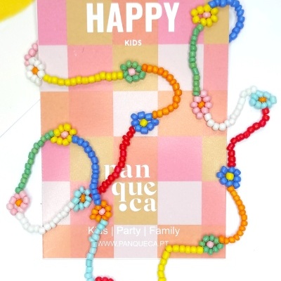 Colar infantil colorido de contas em forma de flores sobre cartão quadriculado com texto