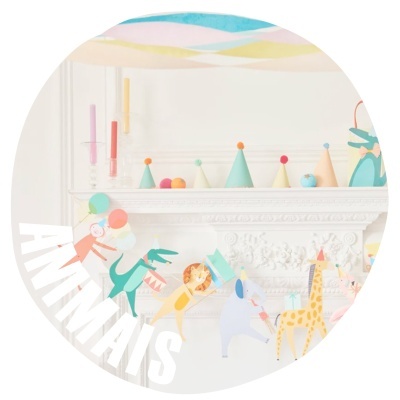 Brinquedos de madeira coloridos com animais e chapéus de festa numa estante branca decorada