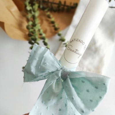 Vela branca decorada com laço azul claro e texto 'BATIZADO Santiago'