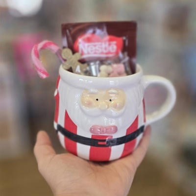 Caneca de Pai Natal com riscas vermelhas e brancas cheia de doces e pacote Nestlé