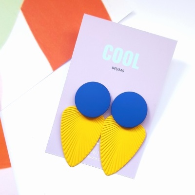 Brincos azul e amarelo em cartão lilás com texto COOL MUMS