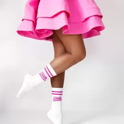 Meias brancas com texto rosa usadas com saia rosa com folhos.