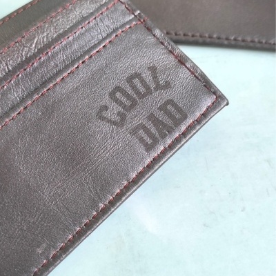 Carteira e estojo de couro castanho escuro com texto COOL DAD na carteira