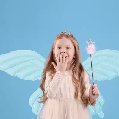 Menina vestida de fada com asas azuis e varinha contra fundo azul