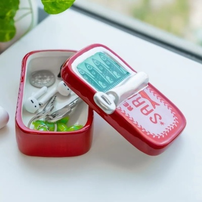 Caixa decorativa vermelha em cerâmica com tampa ilustrada com peixes aberta com chaves e auriculares dentro