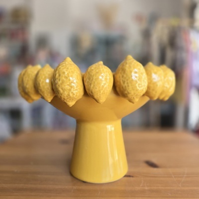 Centro de mesa amarelo em cerâmica com limões decorativos.