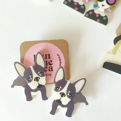 Brincos de bulldog francês em plástico preto, branco e cinza sobre cartão castanho com etiqueta rosa