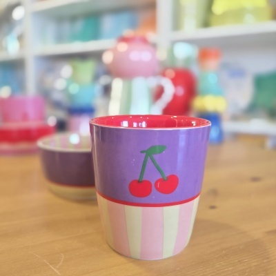 caneca de cerâmica com padrão de cerejas vermelhas sobre fundo roxo e riscas rosa e amarelas