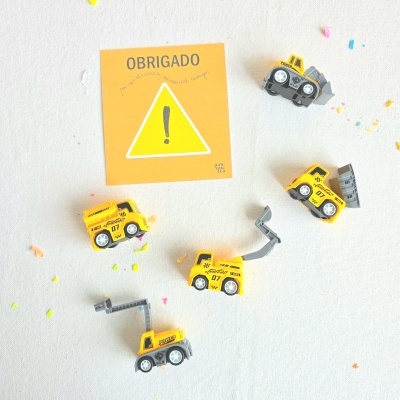 Miniaturas amarelas de veículos de construção com cartão amarelo escrito OBRIGADO