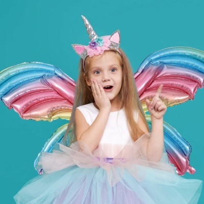 Menina vestida de unicórnio com asas de balão coloridas.