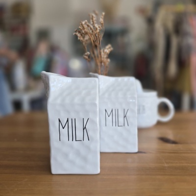Dois jarros de cerâmica branca com a palavra MILK e flores secas