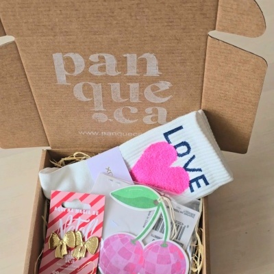 Caixa de cartão castanho aberta com vários acessórios e meias coloridas dentro