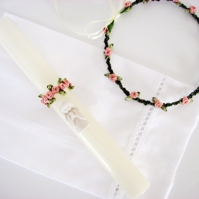 Vela decorada com anjo e coro de flores cor-de-rosa sobre pano branco