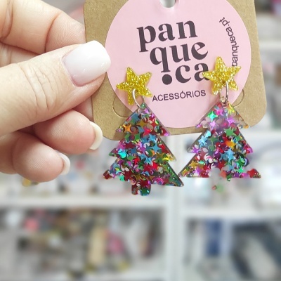 Brincos árvore de Natal coloridos com estrelas amarelas no topo em cartão rosa