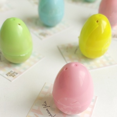 Molhos ou saleiros em forma de ovos coloridos sobre cartões estampados
