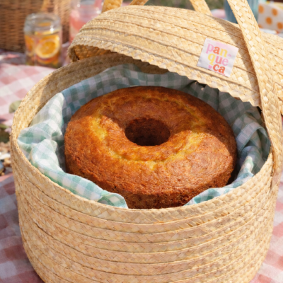 Cesta de palha com bolo dentro sobre toalha xadrez