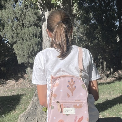 Mochila rosa claro com padrões coloridos usada ao ar livre