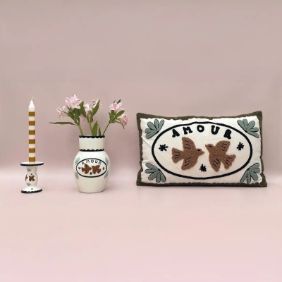 Castiçal com vela, vaso com flores e almofada decorativa com bordado do tema AMOUR