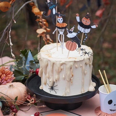 Bolo branco com decoração de Halloween e toppers temáticos numa mesa decorada