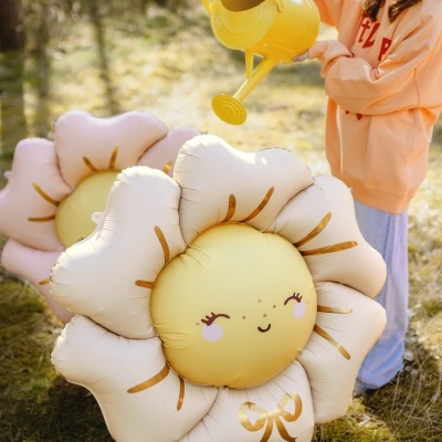 Balão em forma de flor sorridente com menina a usar regador amarelo ao ar livre