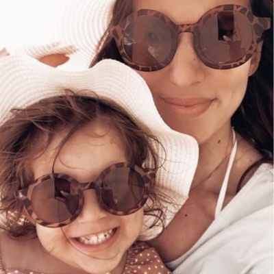 Duas pessoas com óculos de sol padrão tartaruga e roupa clara num ambiente iluminado