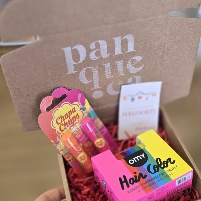 Caixa de cartão com produtos de beleza coloridos em interior com fundo desfocado.