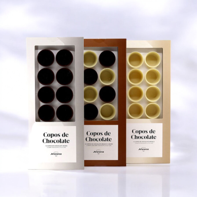 Três caixas de Copos de Chocolate Avianense com copos de chocolate preto, meio amargo e branco visíveis.