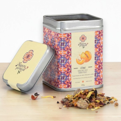 Lata colorida e aberta de chá de melão Piacere Portugal com chá a granel no chão